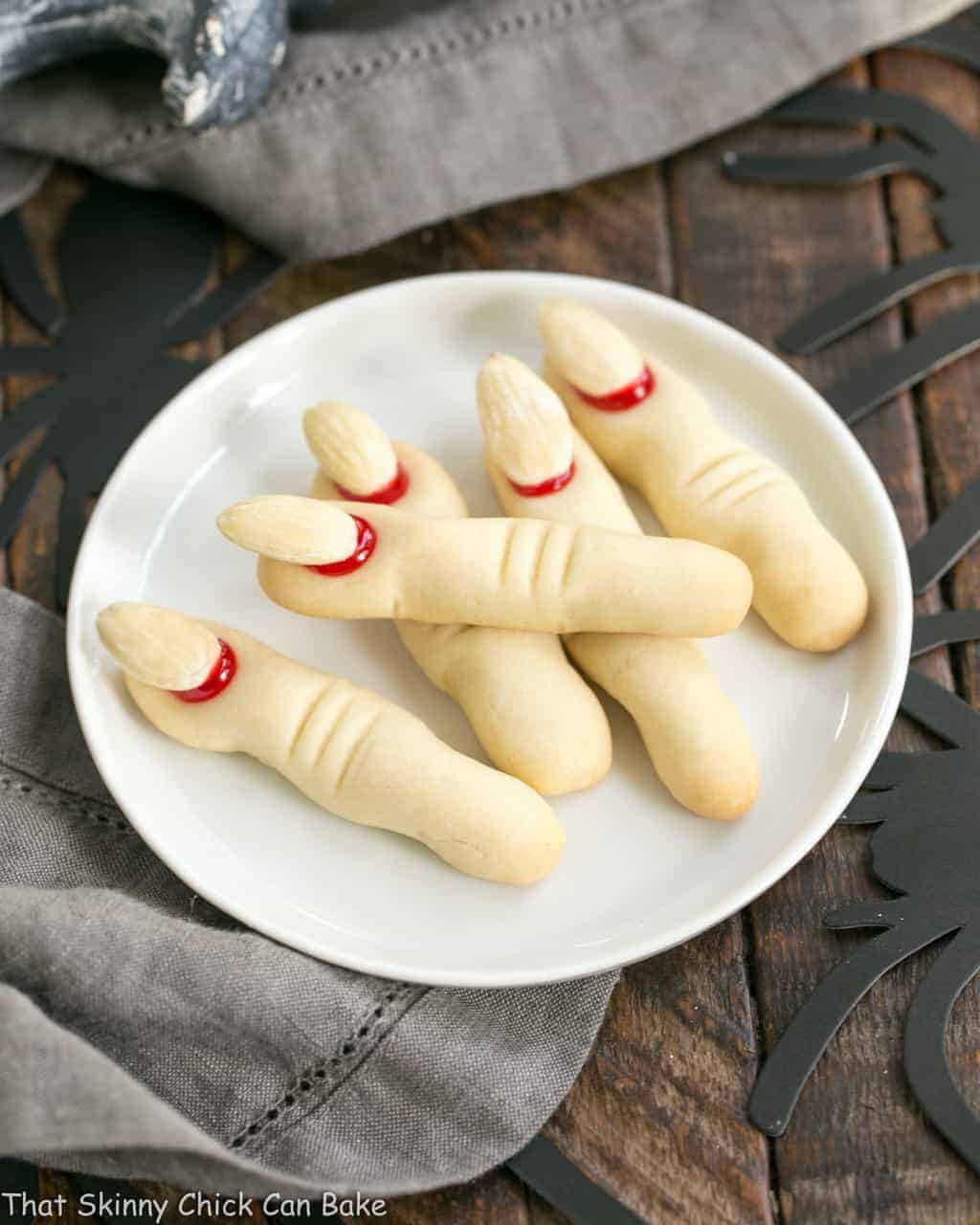 Witches Fingers Cookies - A simple recipe to transform sugar cookie dough into gnarly fingers for Halloween! Witches Fingers Cookies on a round white ceramic plate.